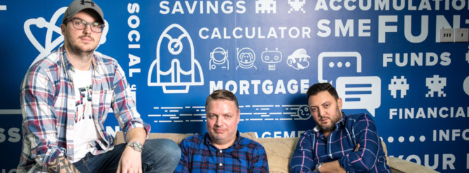 Three male entrepreneurs on a cream  sofa, infront of a blue and white coloured wall